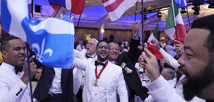 State Deputy Manuel Tomás Tejeda Sánchez of the Dominican Republic (center) and others wave their jurisdictions’ flags during the annual States Dinner on Aug. 5.