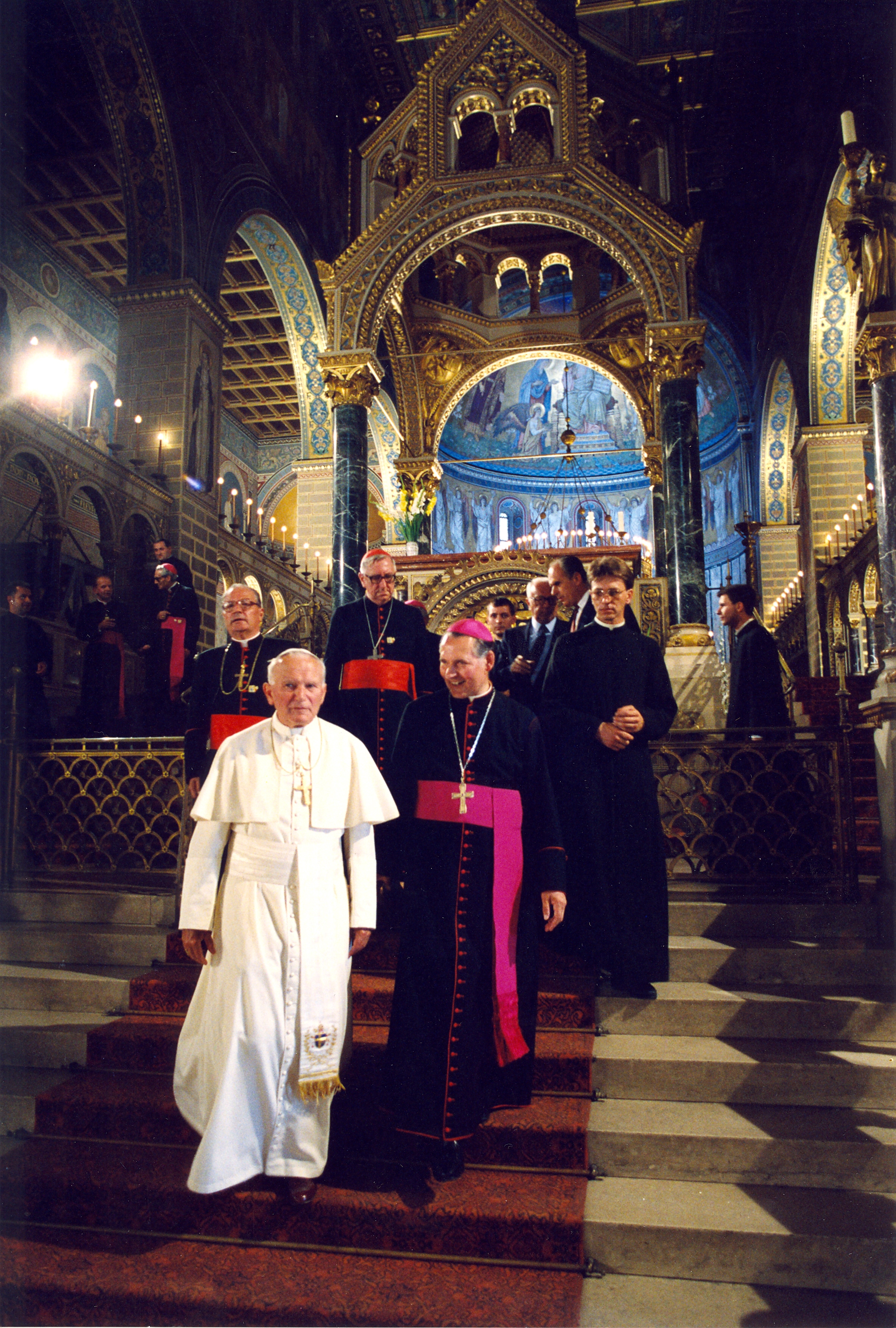 Pope John Paul II Stands with a group of Cardinals inside of a Hungarian Cathedral.