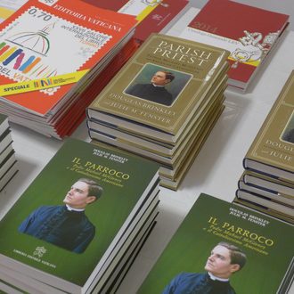 Piles of books from the Knights of Columbus, The biography Parish Priest: Father Michael McGivney and American Catholicism, including the cover of the Italian translation, Il Paroco.