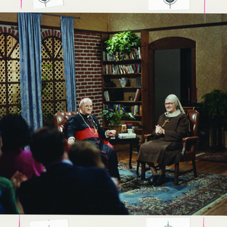 A dated 1981 photo showing a priest and nun being filmed in a library studio during a conversation in front of a live audience.