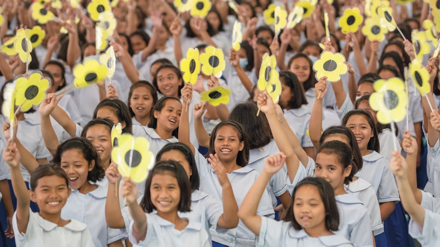 Students wave paper flowers during the Supreme Council delegation’s Aug. 21 visit to Girlstown