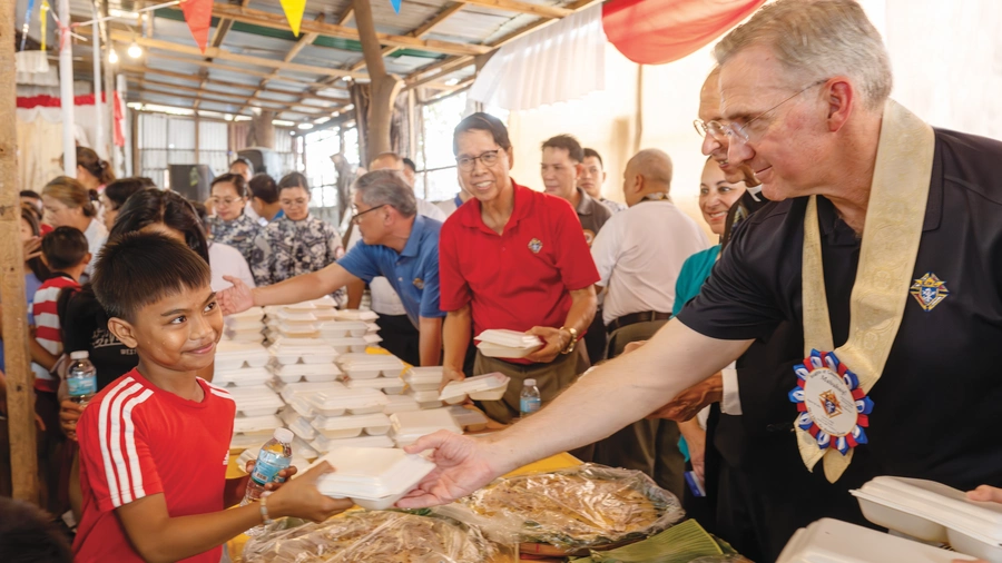 Supreme Knight Patrick Kelly gives a young boy a meal during a parish food distribution