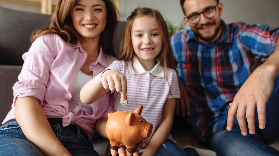 A girl pointing at a piggy bank while sitting with her family