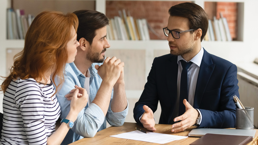 A couple discussing something with a man in a suit