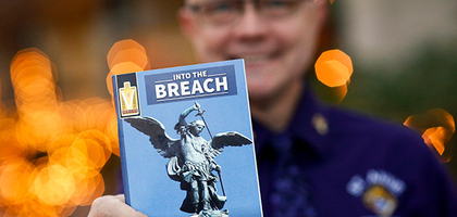 A Knight holding the Booklet “Into the Breach” a part of the Building the Domestic Church initiative.
