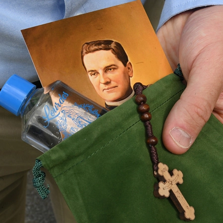 A rosary, a bottle of holy water from Lourdes and a prayer card to Blessed Michael McGivney