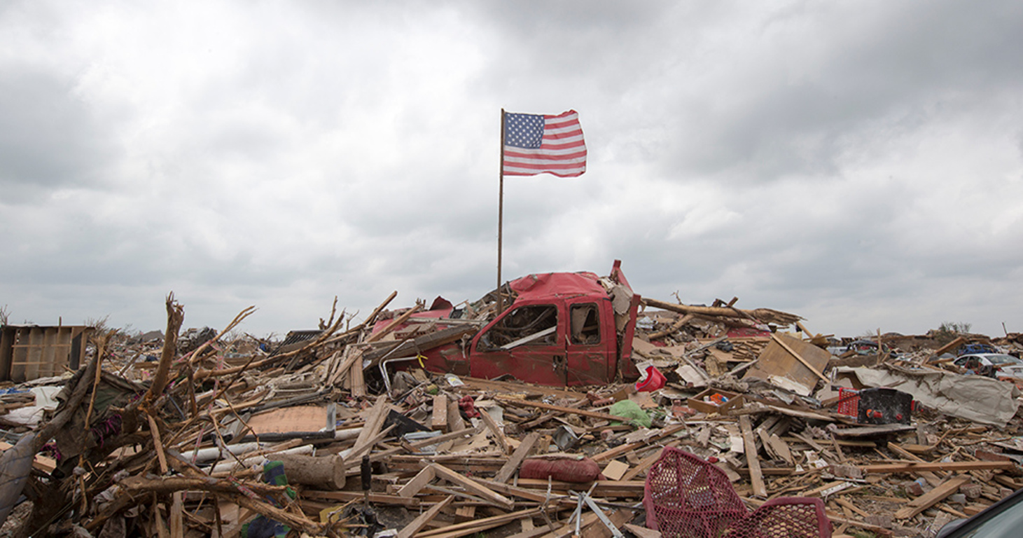 American flag on the top of a pile of debris after a natural disaster.
