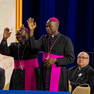 Bishop Matthew Kukah (left) of Sokoto, Nigeria, and Bishop Stephen Mamza (right) of Yola, Nigeria, are recognized during the Aug. 6 business session of the 142nd Supreme Convention in Québec City. In response to rising Christian persecution in Nigeria, the Knights of Columbus will be funding the work of the country’s Catholic bishops to catechize and form their parishioners, Supreme Knight Patrick Kelly announced in his annual report.