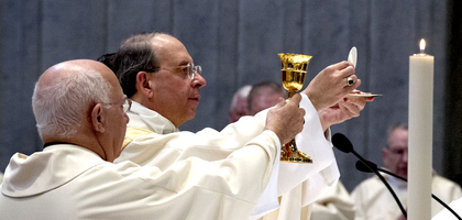 Archbishop Lori holds up the Host during the liturgy of the Eucharist.