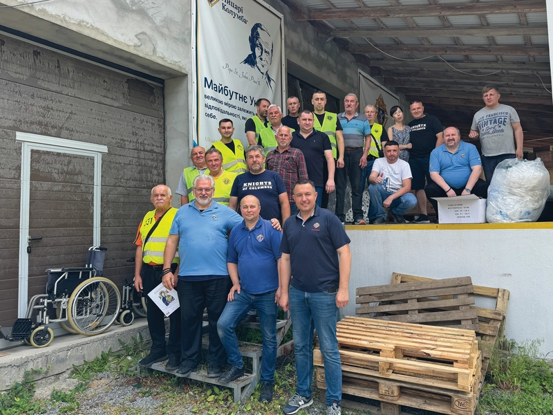 Bishop Bryan Bayda stands with Knights gathered at a K of C distribution warehouse outside Lviv, Ukraine, in June.