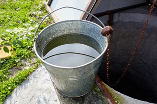 Metal bucket at draw-well in European village.