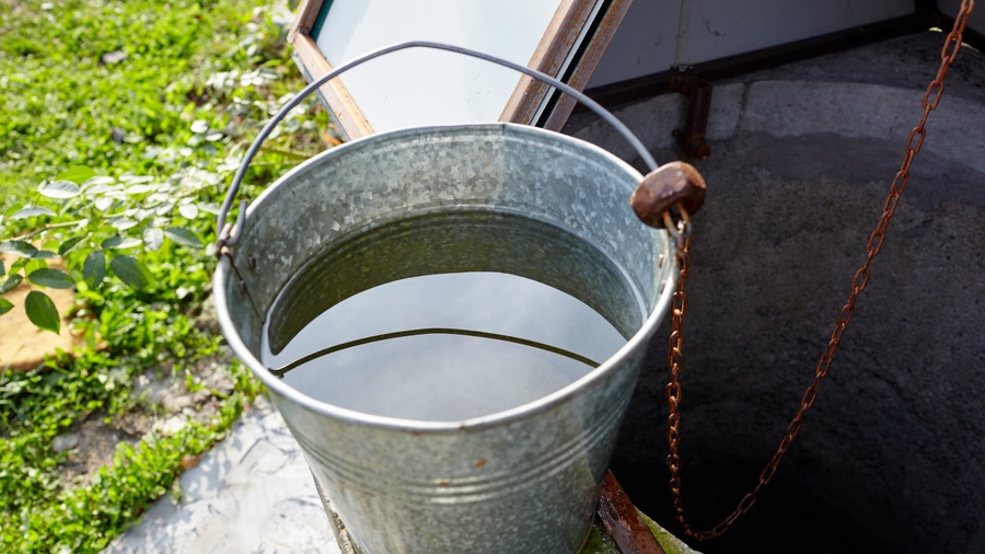 Metal bucket at draw-well in European village.