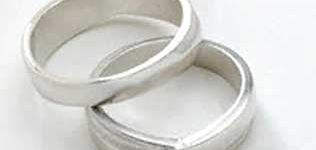 wedding bands overlapping, resting on a white surface