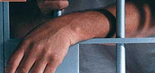 Arms of a prisoner at the door of his prison cell