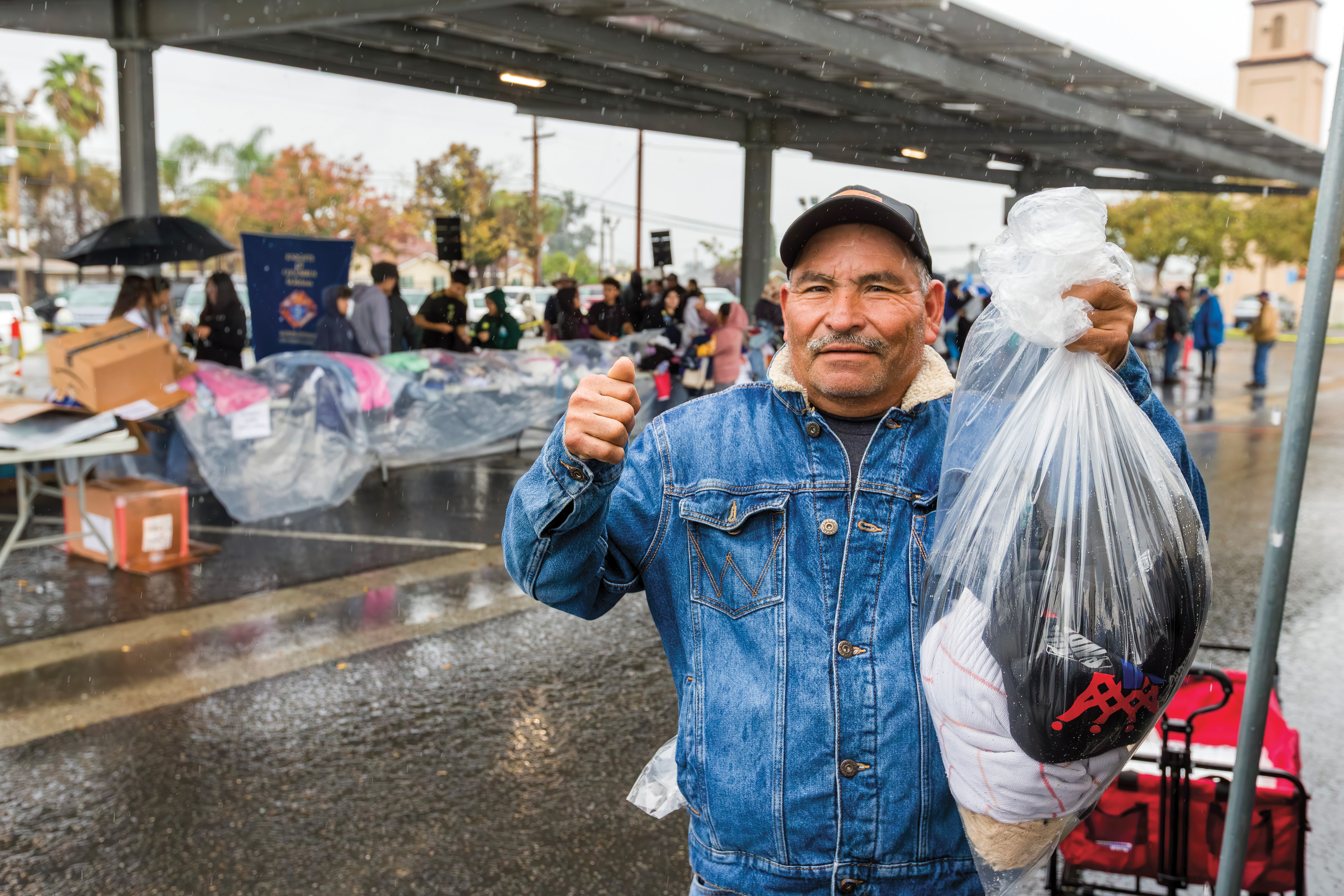 A campesino displays clothes and other goods received during a distribution.