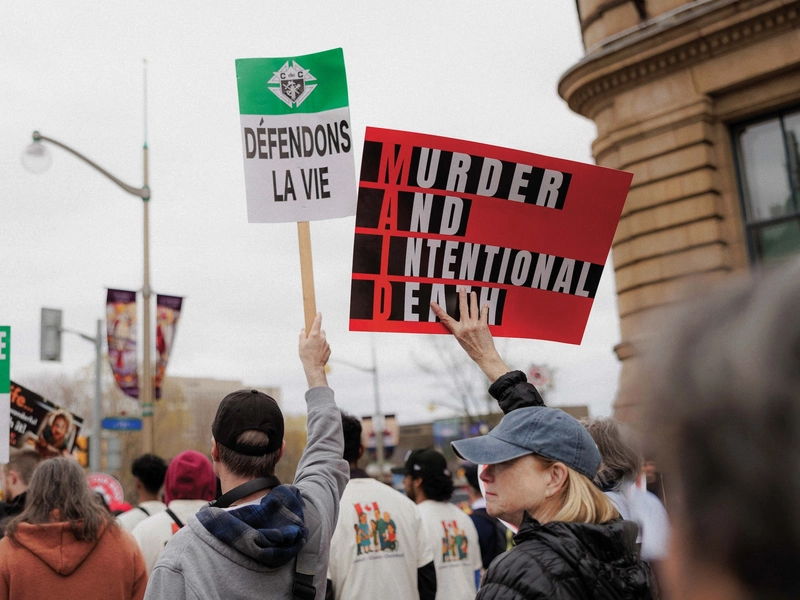 Pro-life advocates display signs defending life and opposing medical assistance in dying.