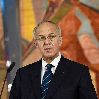 Past Supreme Knight Carl Anderson stands at a podium a the Father McGivney Beatification Mass.