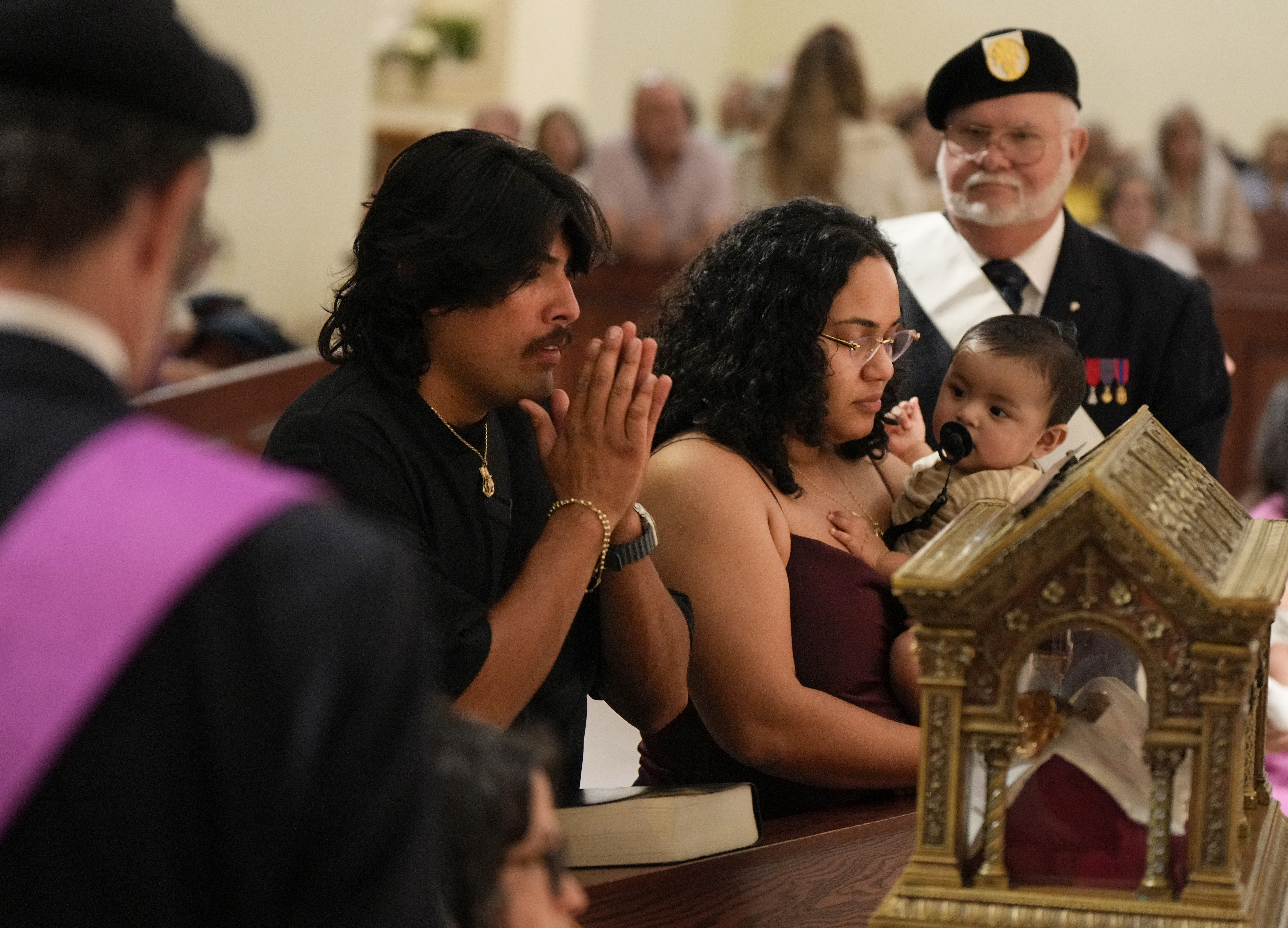 Husband, wife and young son venerate relics of St. Mary Margaret Alacoque in a Church. 