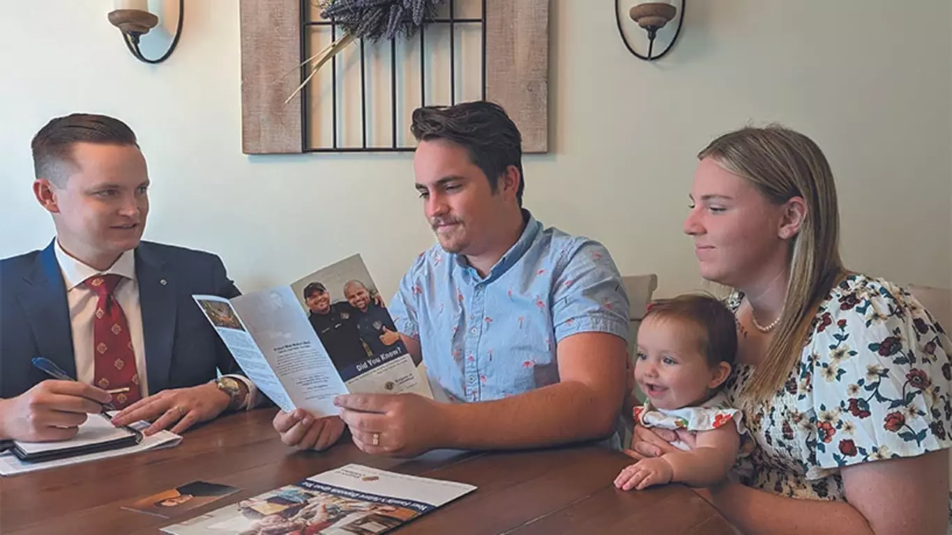 A Knights insurance agent sits at a table with a young family