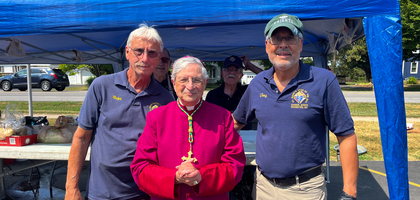Past Grand Knight Antonio Morales (right) and Inside Guard Ralph DiNitto of St. Mark Star of the Sea Council 11374 in Rochester, N.Y., gather with Bishop Salvatore Matano of Rochester at the council’s chicken barbecue sale in the St. Lawrence Church parking lot. Council 11374 organizes about three barbecues each year to support local parishes and charities; the September 2025 event raised more than $1,000.