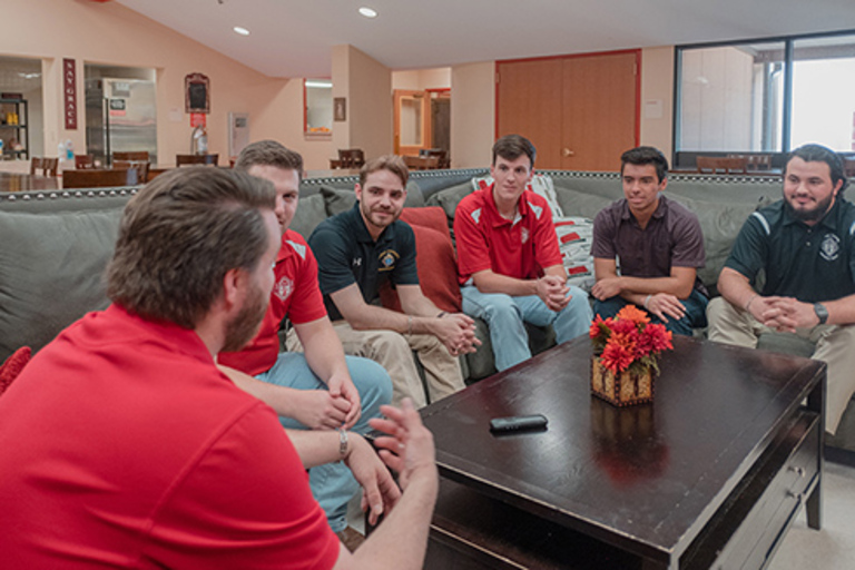 College Knights sit on a couch and talk during a meeting.
