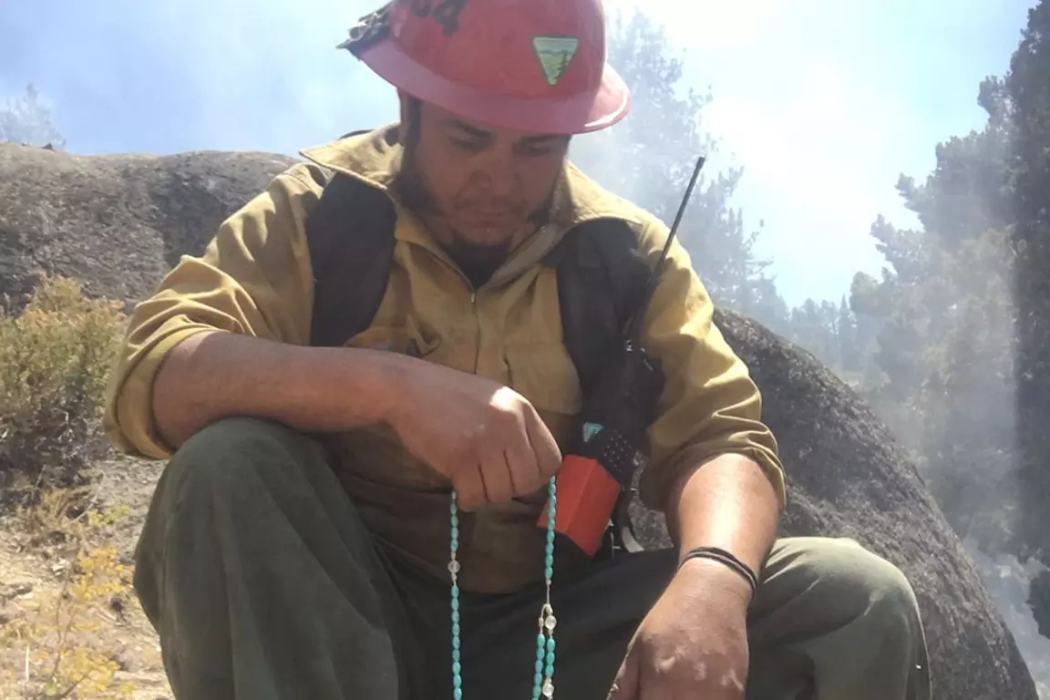 Construction worker, outdoors engaged in a rosary prayer.