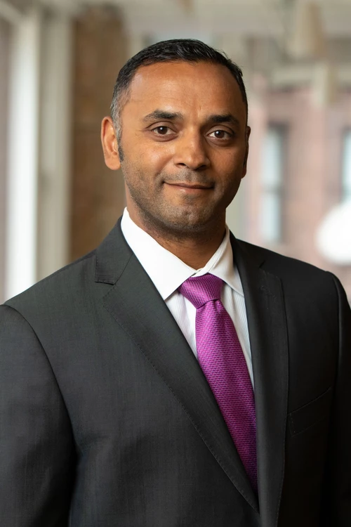 Deepak Devaraj in a dark suit and pink tie.