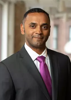 Deepak Devaraj in a dark suit and pink tie.