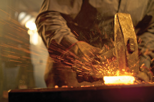 A blacksmith hammers a piece of heated metal.