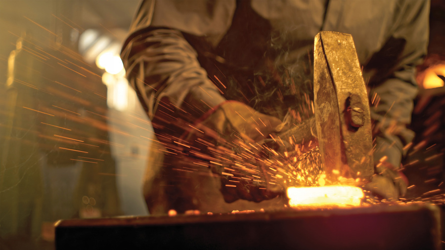 A blacksmith hammers a piece of heated metal.