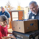 A Knight and child help pack supplies at a food distribution site.