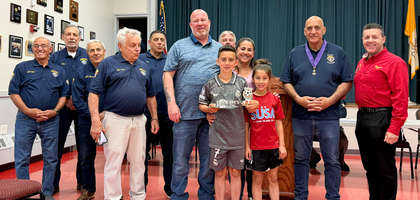 Members of Assumption Council 5252 in East Islip, N.Y., stand with Jordan Beneventin (center, gray shirt) and his family after honoring him as the international champion of the Knights of Columbus Soccer Challenge in his age group. 
