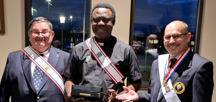 Faithful Navigator Russ Sindelar (right) and Dennis McEnearney of Drumm Assembly 270 in Council Bluffs, Iowa, present a new Mass kit to Father Emmanuel Offiong, a hospital and nursing home chaplain in the area and a brother Knight. Assembly 270 purchased the kit to support his ministry to the sick.