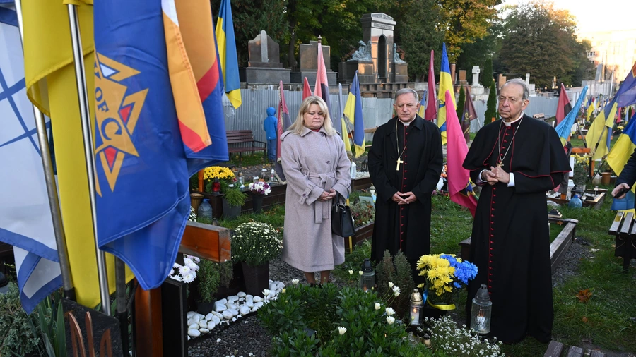 Supreme Chaplain Archbishop William Lori of Baltimore and Archbishop Mieczysław Mokrzycki of Lviv pray at the grave of a fallen soldier at Mars Field in Lviv.