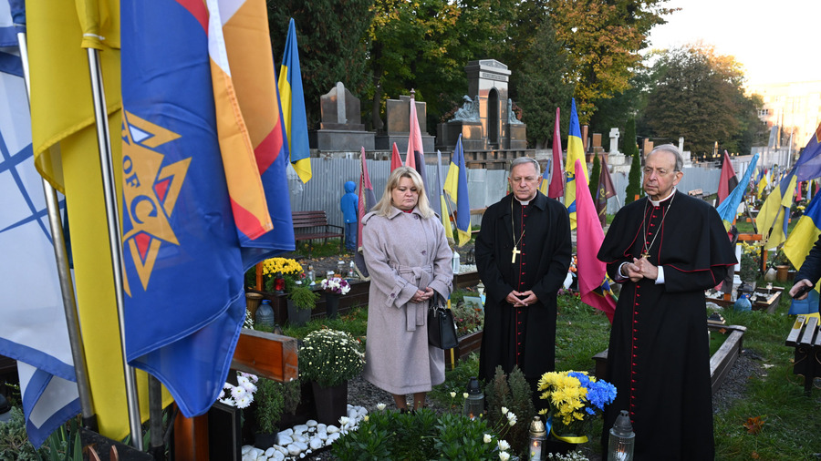 Supreme Chaplain Archbishop William Lori of Baltimore and Archbishop Mieczysław Mokrzycki of Lviv pray at the grave of a fallen soldier at Mars Field in Lviv.