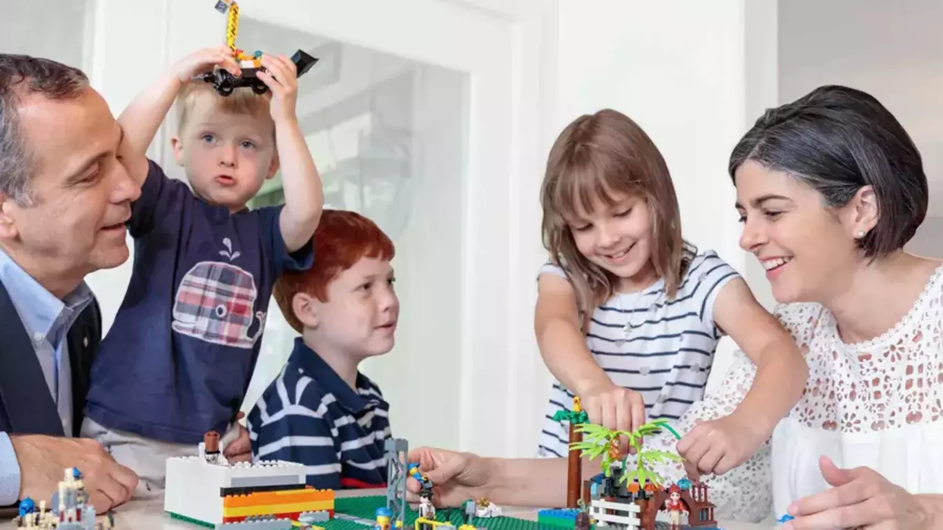 Father building legos with wife and kids knowing he is protecting what matters most.