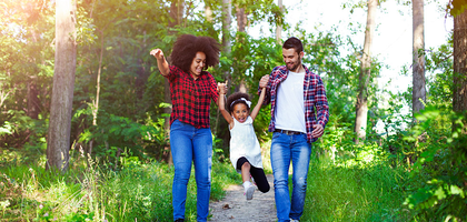 Young daughter swings holding the hands of her parents