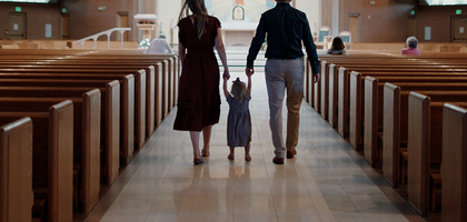A family with a young child walking down the aisle in an empty church. 