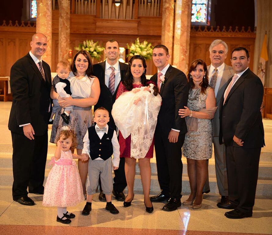 A family poses in a church on the day of a baptism.
