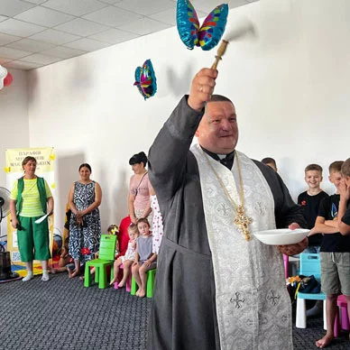 A priest blessing a room with families in it.