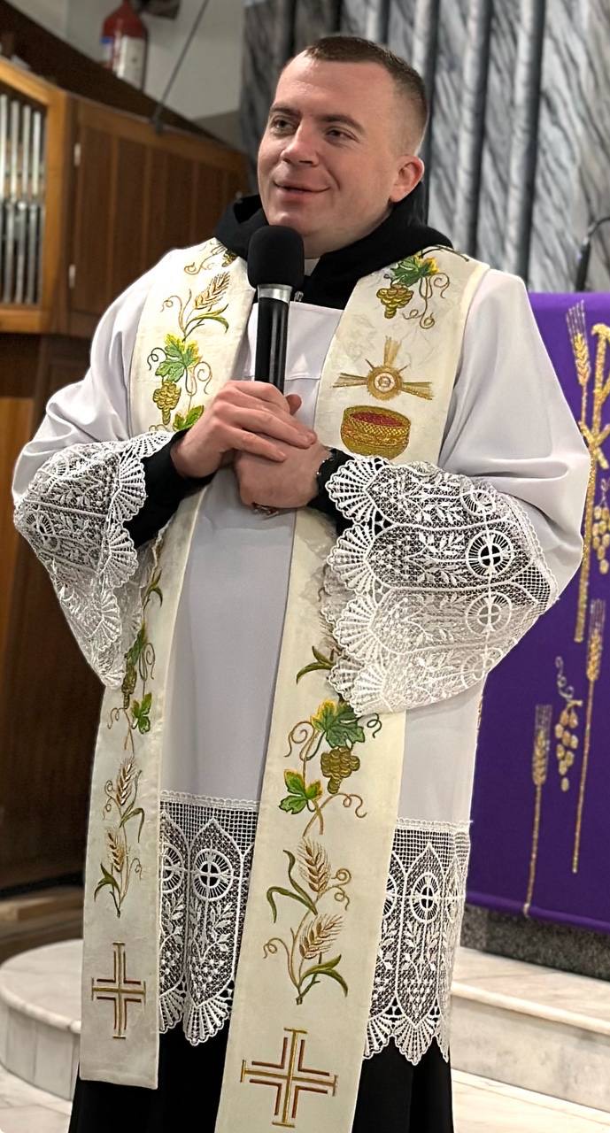 Father Serhii Sviderskyi holding a microphone.