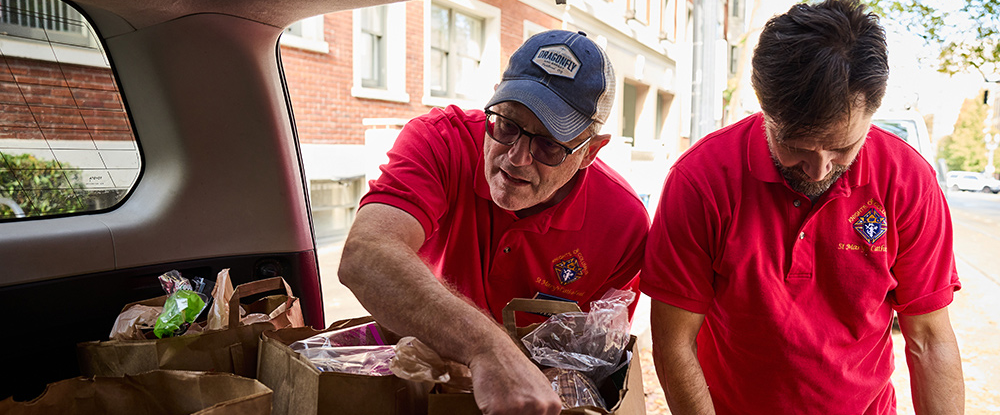 Tim Ferkel (left) and Mark Engelen of St. Mary’s Cathedral of the Immaculate Conception Council 15295 in Portland, Ore., prepare to deliver boxes and bags of food to residents of the Katherine Gray Apartments.