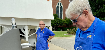 Past Grand Knights Jim Pritchard (right) and Ron Sullivan of Paola (Kan.) Council 1149 cook hot dogs and bratwurst for about 200 parishioners at Holy Trinity Church’s parish picnic. The Knights also prepared funnel cakes and helped with setup and cleanup.