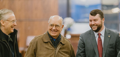 Group of men stand and smile.