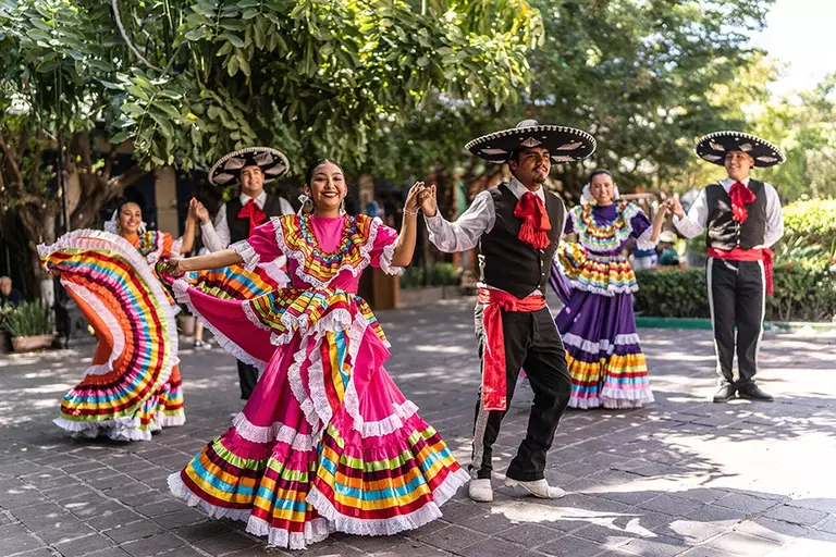 A lively gathering of people dancing and dressed in colorful attire, representing cultural heritage and festive spirit.