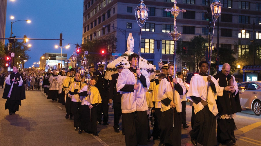 People process behind the “Broken Mary” statue down Chicago Avenue after leaving St. John Cantius Church on May 31, 2019.