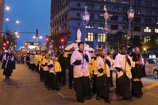 People process behind the “Broken Mary” statue down Chicago Avenue after leaving St. John Cantius Church on May 31, 2019.