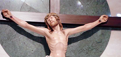 Statue in skin color and real wood depicting Jesus on the cross with crown of thorns.