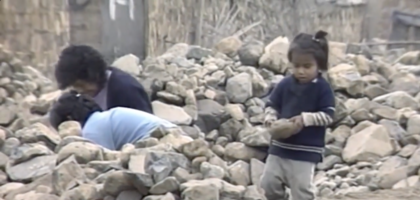 Young children sort through rubble.