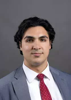 Headshot of Joseph Rafala, who smiles while wearing a gray suit and a red tie.